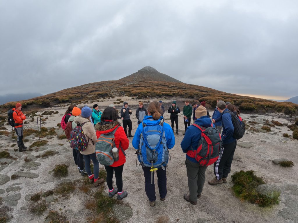 A group of hikers stand in a circle on the path to Slieve Doan in Northern Ireland, practising mindfulness.